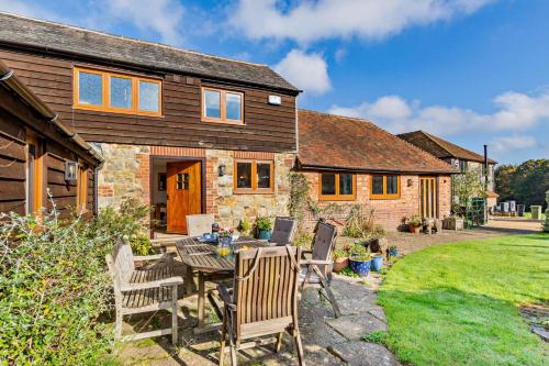 a stone house with a table and chairs in the yard at The Granary - Ticehurst in Ticehurst
