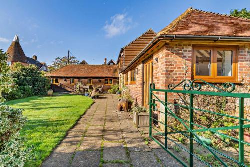 a brick house with a green gate in front of it at The Granary - Ticehurst in Ticehurst