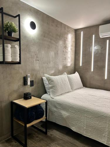 ein kleines Schlafzimmer mit einem Bett und einem Beistelltisch in der Unterkunft Departamento Moderno con balcón y piscina climatizada in Rosarito Beach