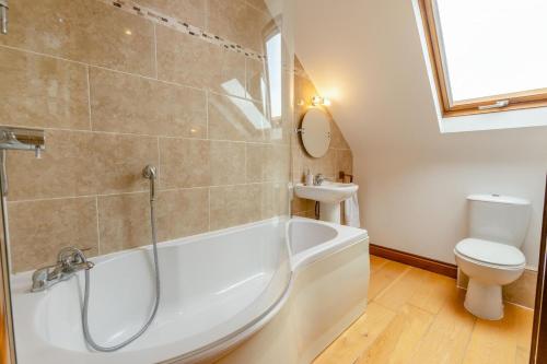 a bathroom with a tub and a toilet and a sink at Marazion Sail Loft in Marazion