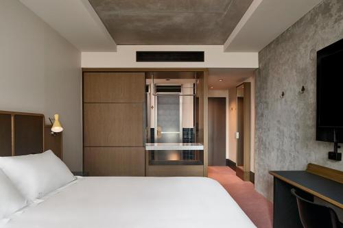 a bedroom with a large white bed and a television at Hannah St Hotel Melbourne in Melbourne