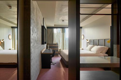 a hotel room with two beds and a desk at Hannah St Hotel Melbourne in Melbourne