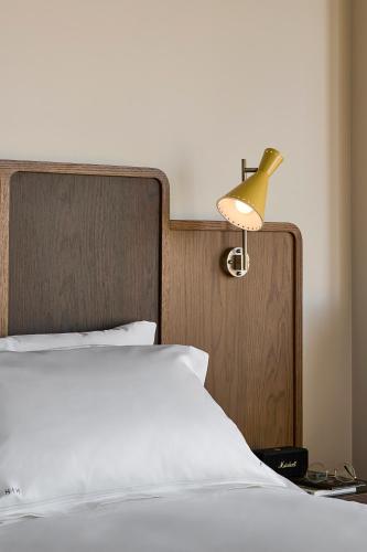 a bed with a wooden head board and a lamp at Hannah St Hotel Melbourne in Melbourne