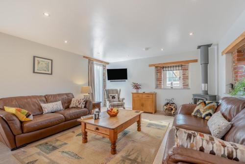 a living room with leather couches and a coffee table at Paxton View Barn - Llanddarog in Llanddarog