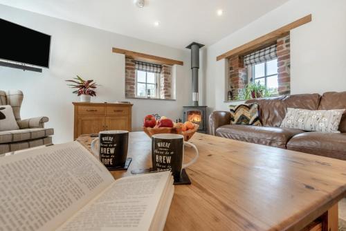 a living room with a table with a book at Paxton View Barn - Llanddarog in Llanddarog