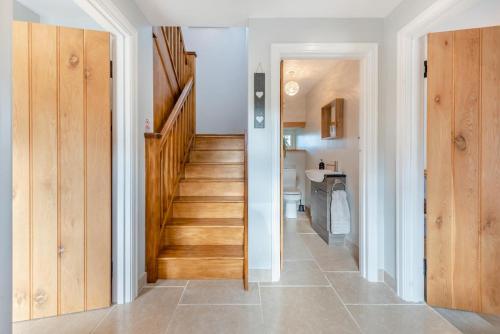 a hallway with a wooden staircase and a bathroom at Paxton View Barn - Llanddarog in Llanddarog