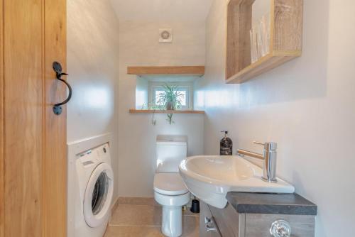 a bathroom with a sink and a washing machine at Paxton View Barn - Llanddarog in Llanddarog