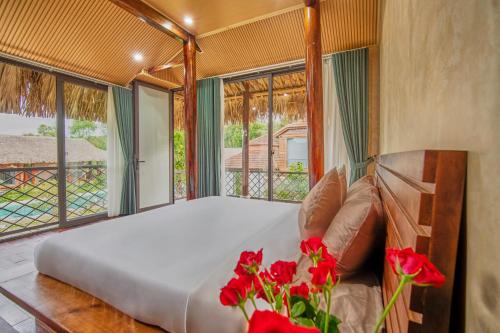 a bed with red flowers in a room with windows at Lá Retreat near Ba Na Hills in Thôn Phước Sơn