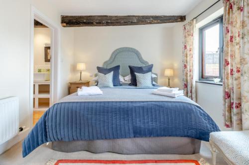 a bedroom with a blue bed with blue and white pillows at The Holt Barn in Tong