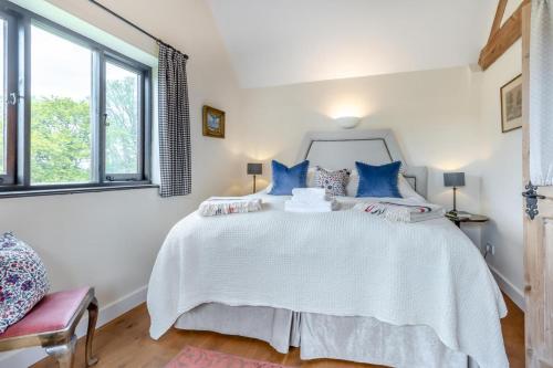 a bedroom with a large white bed with blue pillows at The Holt Barn in Tong