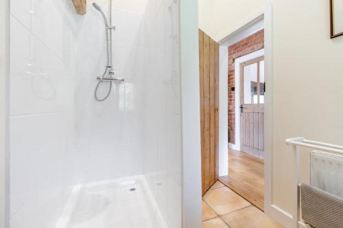a bathroom with a shower and a white tub at The Holt Barn in Tong