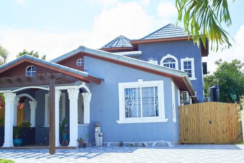 a blue house with a fence in front of it at Pergola House 1 or 2 bedrooms in Montego Bay