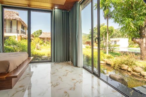 a bedroom with large windows and a bed with a view at Lá Retreat near Ba Na Hills in Thôn Phước Sơn