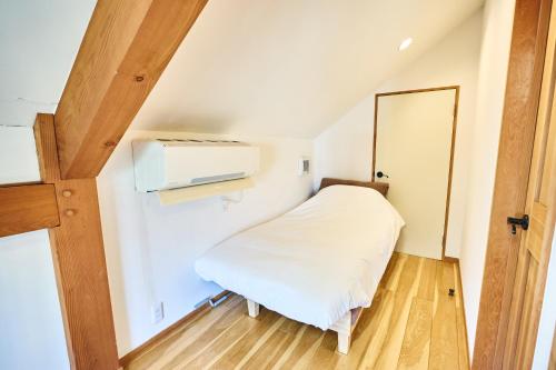 a small room with a bed and a microwave at TOOD一宮 -B棟 in Ichinomiya