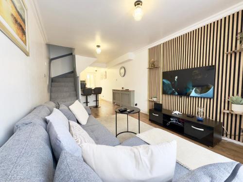 a living room with a blue couch and a flat screen tv at The Cozy Hideaway - 2 Bedroom apartment with garden in Orpington with free Parking in Foots Cray