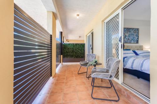 a bedroom with a bed and two chairs in a room at Parkside Villa on the Creek in Redcliffe