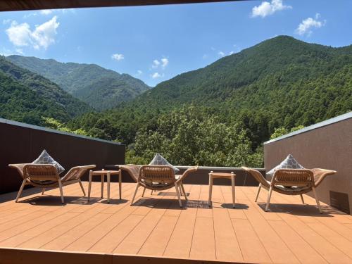 a deck with chairs and a table with mountains in the background at 大同ガーデンホテル湯の山リゾート in Wada