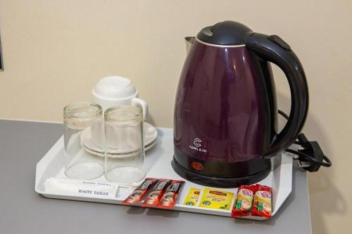 a tea kettle and glasses on a tray on a counter at Southern Tip Hotel - City & 100m walk to McDonald's & FREE DOBI in Pontian Kecil