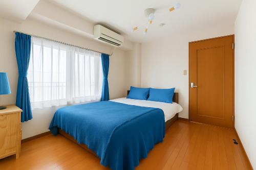 a bedroom with a blue bed and a window at Cozy Apartment, 2min to Station , Direct to Skytree, Asakusa & Ueno & Narita ,駅2分,スカイツリー浅草上野成田空港直結,エレベーター,スーパー2分,コンビニ1分 in Tokyo