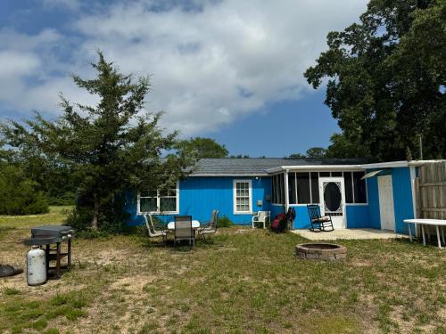 a blue house with a table and chairs in a yard at Family Cottage 1 mile to Carolina Beach in Wilmington