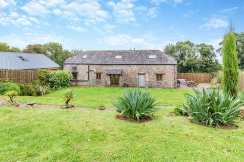 an old stone house in a yard with plants at The Moohey in Downderry
