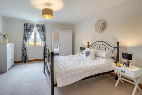 a bedroom with a bed and a desk and a window at Coed Y Nant Barn in Cilybebyll