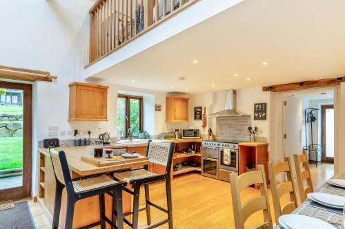 a large kitchen with a wooden table and chairs at The Moohey in Downderry