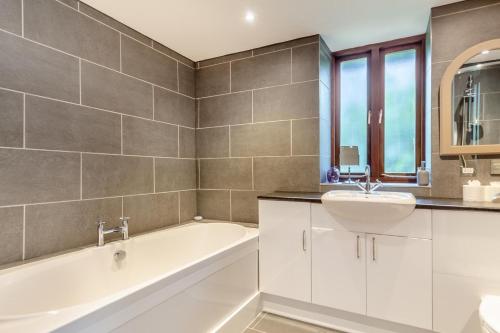 a bathroom with a white tub and a sink at The Moohey in Downderry