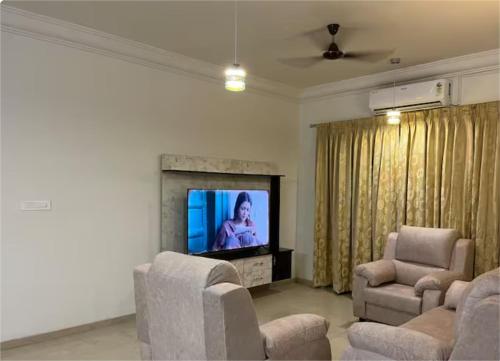a living room with a television and two chairs at Urban Stay Service Apartments Oragadam in Oragadam