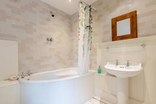 a bathroom with a sink and a tub and a toilet at Bonnings Cottage in Barrington