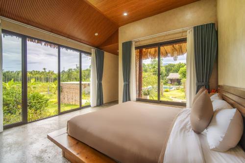 a bedroom with a large bed and large windows at Lá Retreat near Ba Na Hills in Thôn Phước Sơn