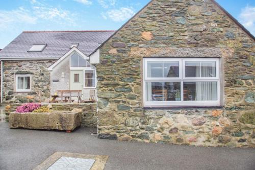 a stone house with a window on the side of it at Fferm Cwt Drecs in Llanfaethlu