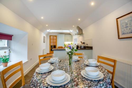 a dining room with a table with plates and bowls at Fferm Cwt Drecs in Llanfaethlu
