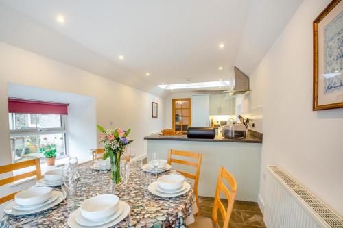 a dining room with a table and chairs and a kitchen at Fferm Cwt Drecs in Llanfaethlu