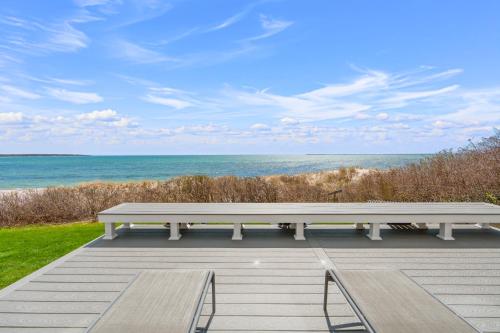 a bench sitting on a deck looking at the ocean at Hydrangeas by the Sea in Barnstable