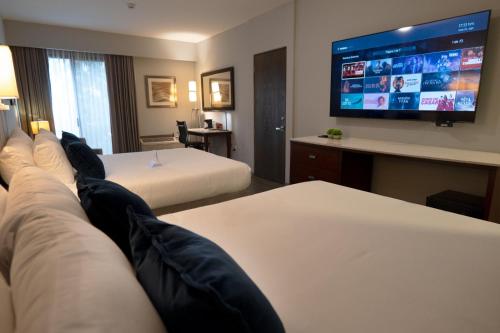 a hotel room with two beds and a flat screen tv at Esplendor by Wyndham Los Mochis Country Place in Los Mochis