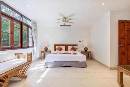 a bedroom with a bed and a couch and windows at Kamala Beach Estate Resort - SHA Extra Plus in Kamala Beach
