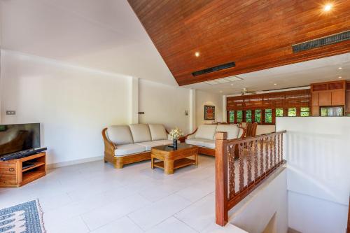 a living room with a couch and a tv at Kamala Beach Estate Resort - SHA Extra Plus in Kamala Beach