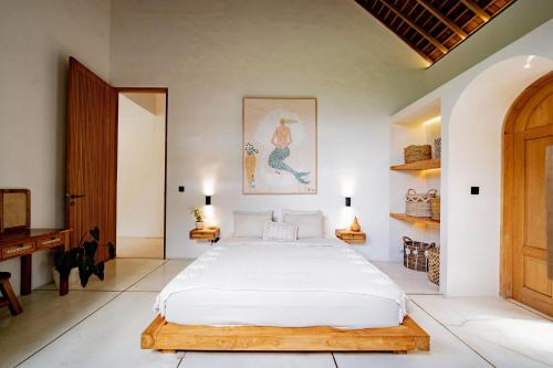 a bedroom with a large white bed and a desk at Villa Kerang Sue in Munggu