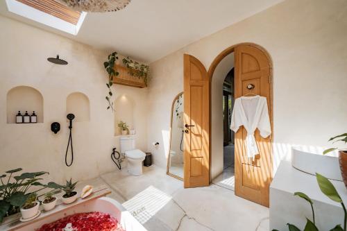 a bathroom with a toilet and a wooden door at Villa Kerang Sue in Munggu