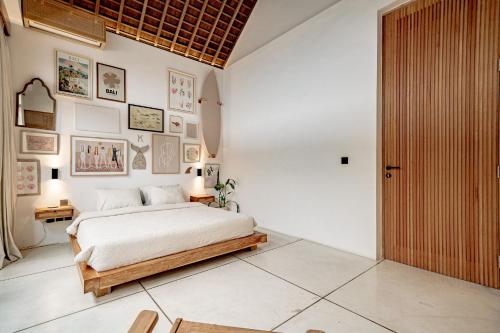 a bedroom with a bed and some pictures on the wall at Villa Kerang Sue in Munggu