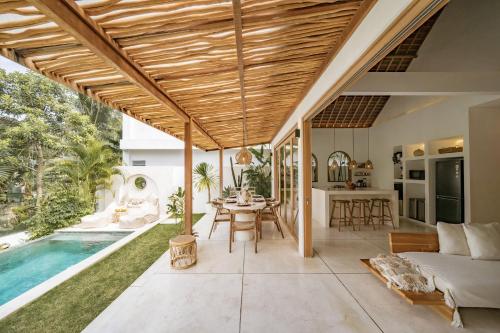 an open living room with a pool and a house at Villa Kerang Sue in Munggu