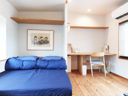 - une chambre avec un lit bleu et un bureau dans l'établissement Kamogawa Sanpo, à Shimmachidōri