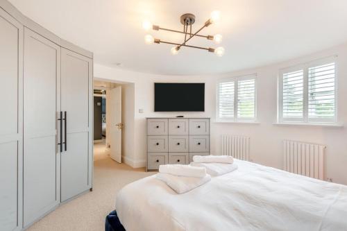 a white bedroom with a bed and a tv at Criol Oast in Shadoxhurst