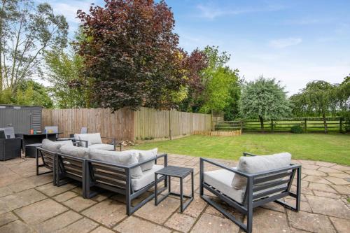 a patio with chairs and tables and a fence at Criol Oast in Shadoxhurst