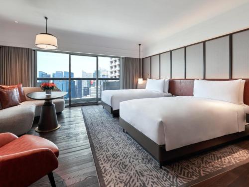 a hotel room with two beds and a couch at Fairmont Singapore in Singapore