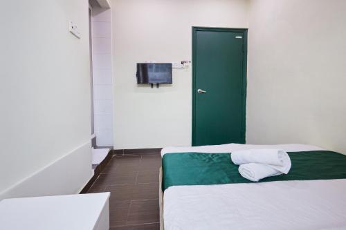 a room with a bed with a green door and a television at Fast Hotel Sri Gombak in Batu Caves