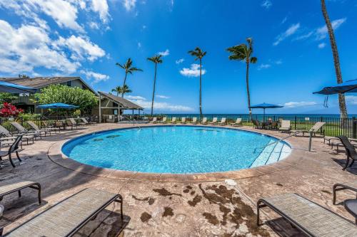 a swimming pool with chairs and the ocean in the background at Kahana Village 32 · KHV 32 Direct Oceanfront Views Remodeled 2BD in Kahana