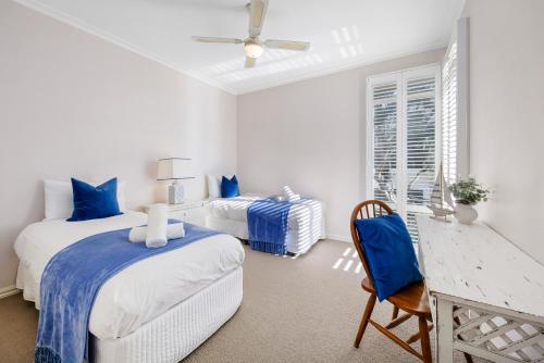 a white bedroom with two beds and a chair at Serendib Luxury Sorrento Resort Living in Sorrento