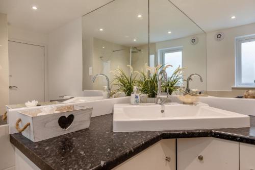 Un baño con lavabo y un espejo grande. en Ocean Villa, en Woolacombe